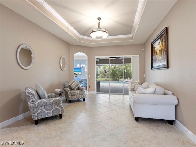 living area featuring baseboards, a tray ceiling, ornamental molding, light tile patterned floors, and arched walkways