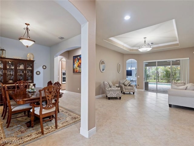 dining space featuring baseboards, arched walkways, a raised ceiling, and light tile patterned flooring