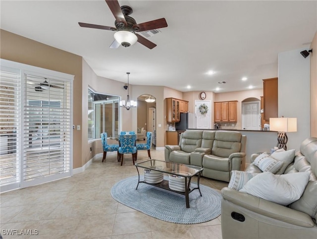 living room featuring ceiling fan with notable chandelier, recessed lighting, arched walkways, light tile patterned floors, and baseboards