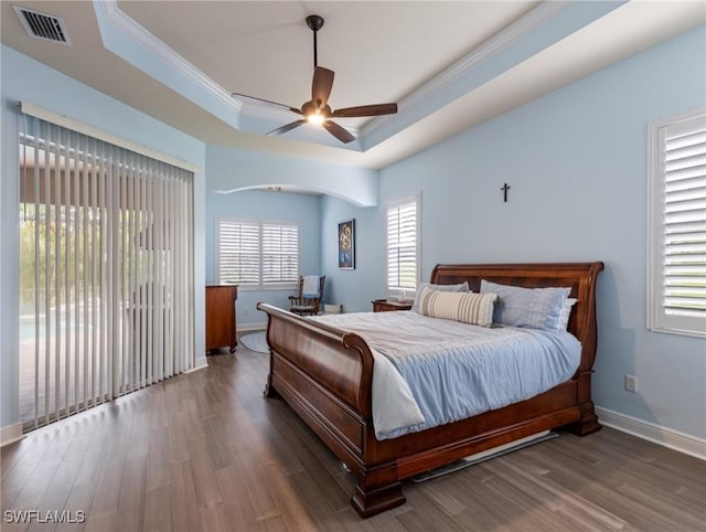 bedroom featuring wood finished floors, visible vents, baseboards, a tray ceiling, and access to exterior