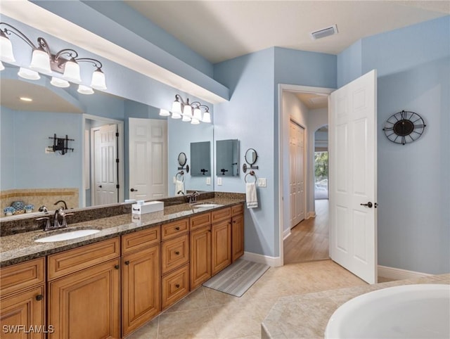 bathroom featuring a sink, visible vents, double vanity, and tile patterned floors