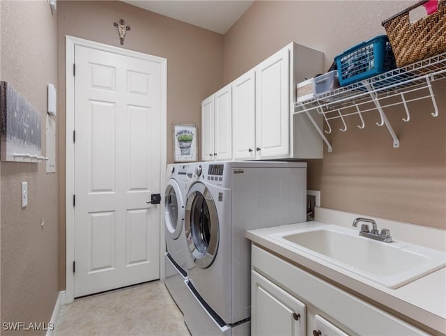 clothes washing area featuring a sink, cabinet space, a textured wall, and washing machine and clothes dryer