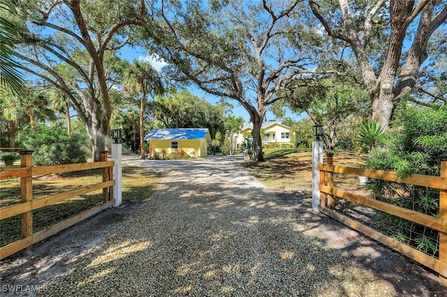 3643 N Rd, Naples, FL 34104 - view of yard featuring an outdoor structure, fence, and gravel driveway