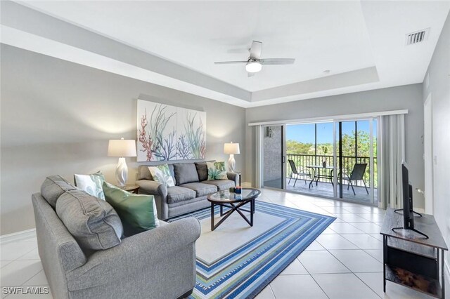 7831 Regal Heron Cir Unit 304, Naples, FL 34104 - living room featuring a tray ceiling, light tile patterned floors, ceiling fan, and baseboards