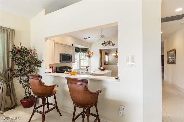 kitchen featuring decorative light fixtures, stainless steel microwave, a breakfast bar area, light countertops, and stove