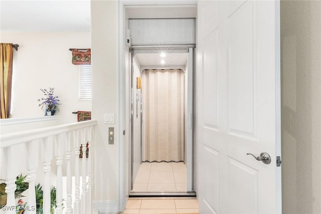 corridor with elevator and tile patterned flooring