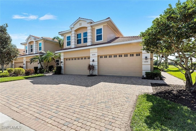 view of front of house with stucco siding, a tiled roof, and decorative driveway