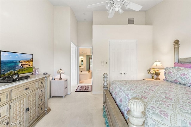 bedroom with visible vents, a high ceiling, a closet, ensuite bathroom, and light carpet