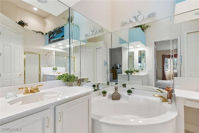 ensuite bathroom with ensuite bath, two vanities, a stall shower, a sink, and a garden tub