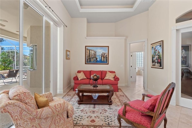 living room with light tile patterned floors, baseboards, and a raised ceiling