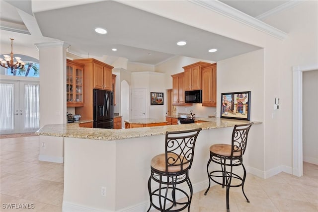 kitchen featuring black appliances, glass insert cabinets, light stone countertops, and ornamental molding