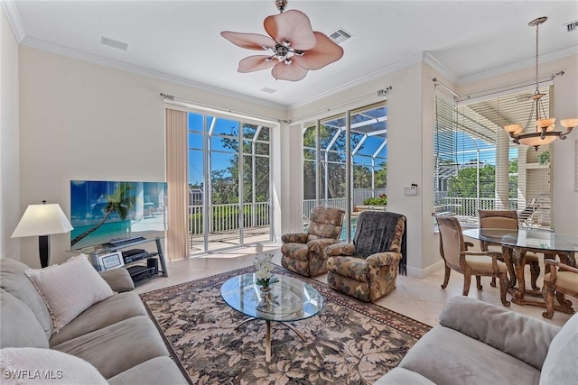 living area with tile patterned flooring, crown molding, ceiling fan with notable chandelier, and visible vents