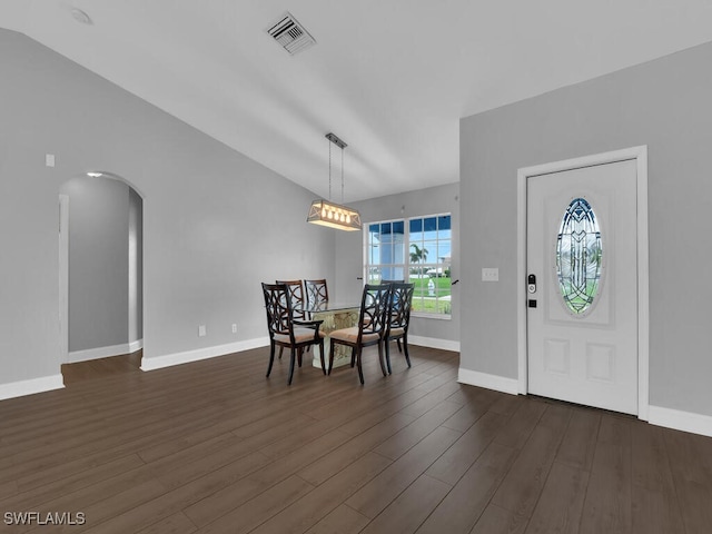 dining area featuring visible vents, dark wood-type flooring, arched walkways, baseboards, and vaulted ceiling