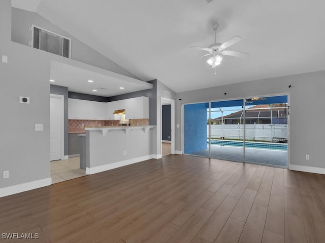 unfurnished living room featuring visible vents, high vaulted ceiling, light wood-style floors, baseboards, and ceiling fan