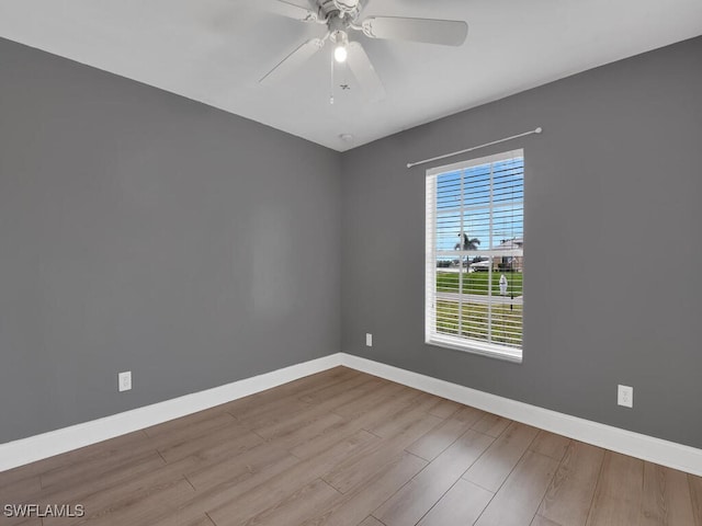 spare room featuring baseboards, wood finished floors, and a ceiling fan