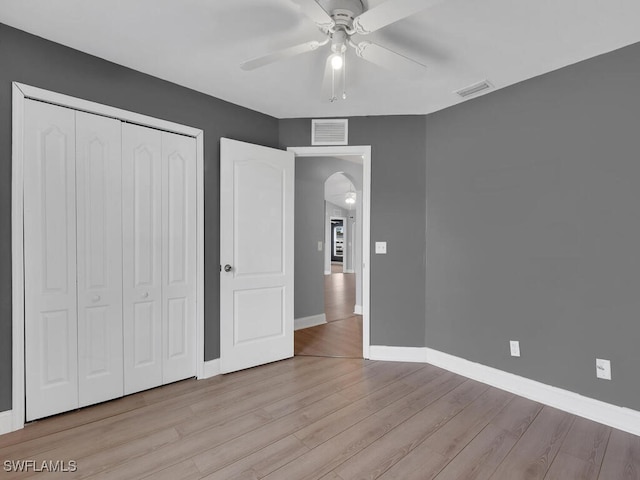 unfurnished bedroom featuring a closet, visible vents, baseboards, and wood finished floors