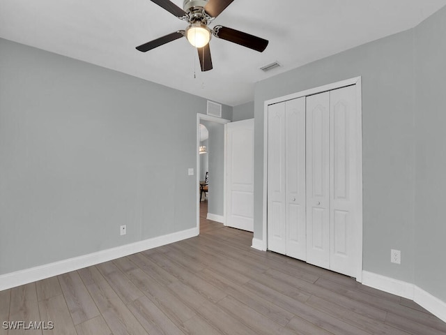 unfurnished bedroom featuring wood finished floors, visible vents, a closet, and baseboards