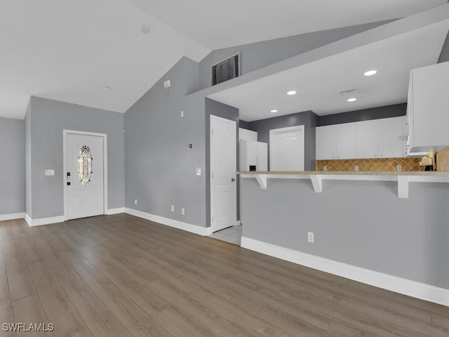 entrance foyer with visible vents, lofted ceiling, baseboards, and wood finished floors