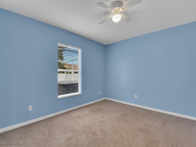 carpeted empty room with baseboards and a ceiling fan