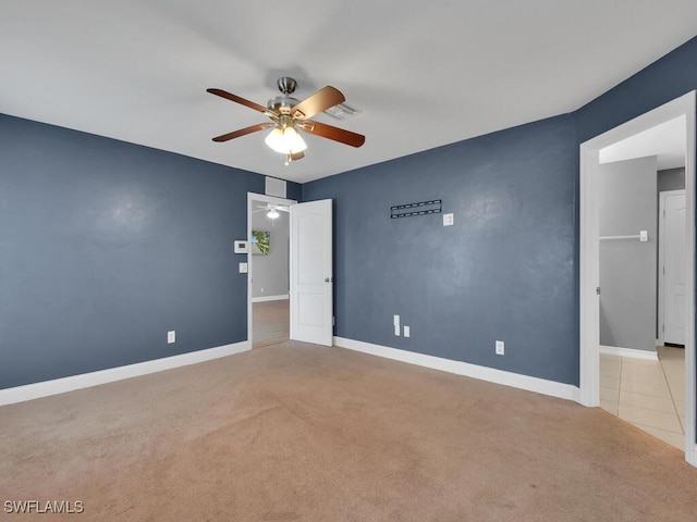 carpeted spare room with visible vents, baseboards, and ceiling fan