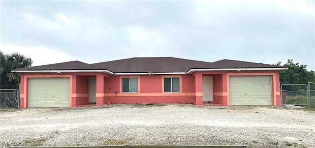 ranch-style house with a garage, fence, roof with shingles, and stucco siding