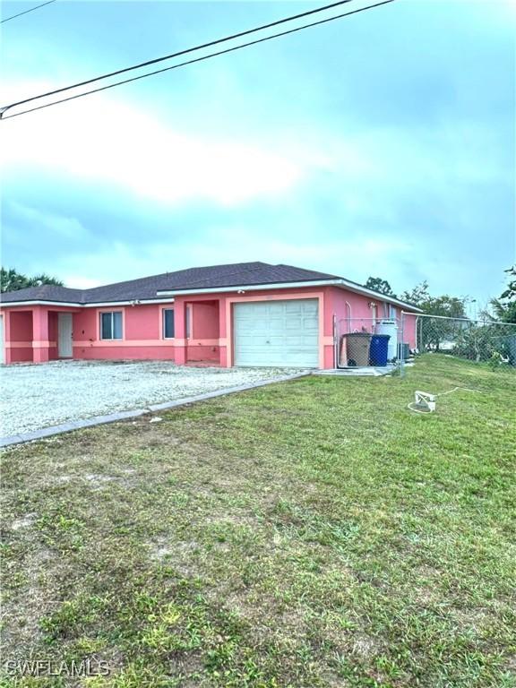 ranch-style home with stucco siding, driveway, and a front lawn