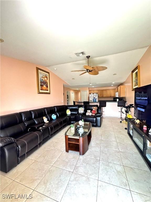 living room with light tile patterned floors, visible vents, lofted ceiling, and a ceiling fan