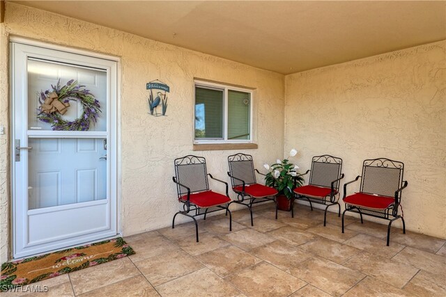 view of exterior entry with stucco siding and a patio