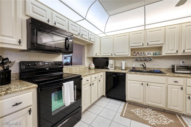 kitchen featuring a sink, decorative backsplash, black appliances, and white cabinetry