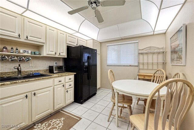 kitchen with tasteful backsplash, ceiling fan, black refrigerator with ice dispenser, marble finish floor, and a sink