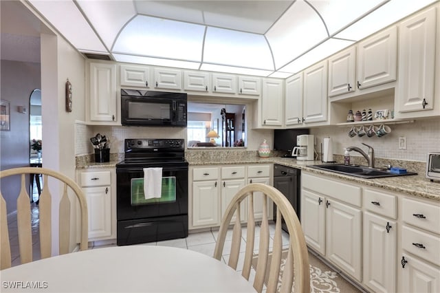 kitchen with a sink, tasteful backsplash, black appliances, and white cabinets