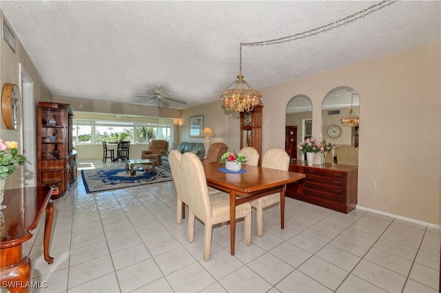 dining space with arched walkways, ceiling fan with notable chandelier, a textured ceiling, and light tile patterned flooring