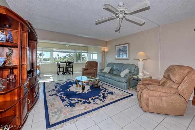 living area with ceiling fan, a textured ceiling, and light tile patterned flooring