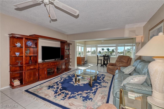 living room with baseboards, a textured ceiling, a ceiling fan, and tile patterned flooring