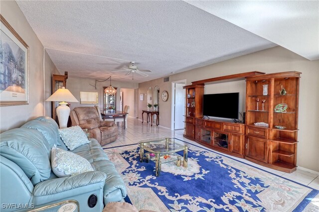 living room with tile patterned flooring, visible vents, baseboards, ceiling fan, and a textured ceiling