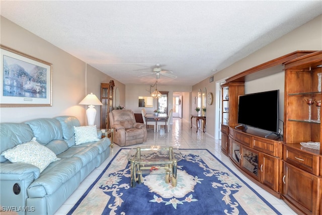 living area featuring light tile patterned floors, ceiling fan with notable chandelier, and a textured ceiling