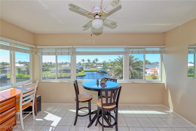 sunroom / solarium featuring ceiling fan and a water view