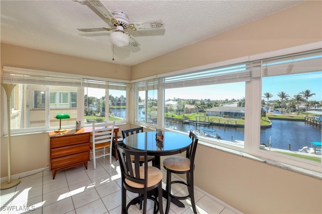 sunroom with a water view, a healthy amount of sunlight, and a ceiling fan