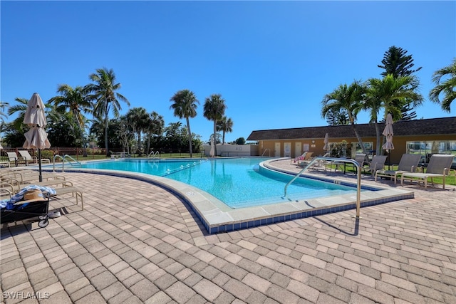 community pool with fence and a patio area