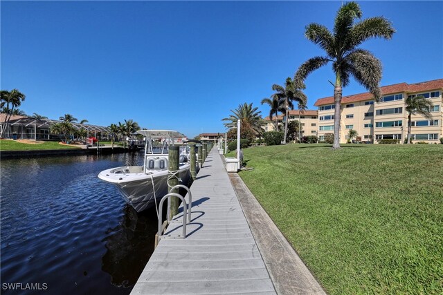 view of dock with a lawn and a water view