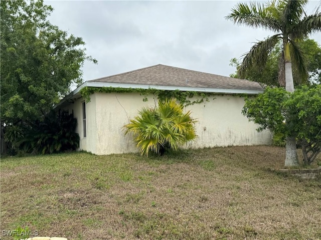 view of property exterior featuring stucco siding, a lawn, and a shingled roof