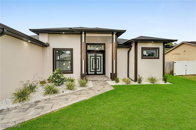 property entrance featuring stucco siding, a lawn, and fence