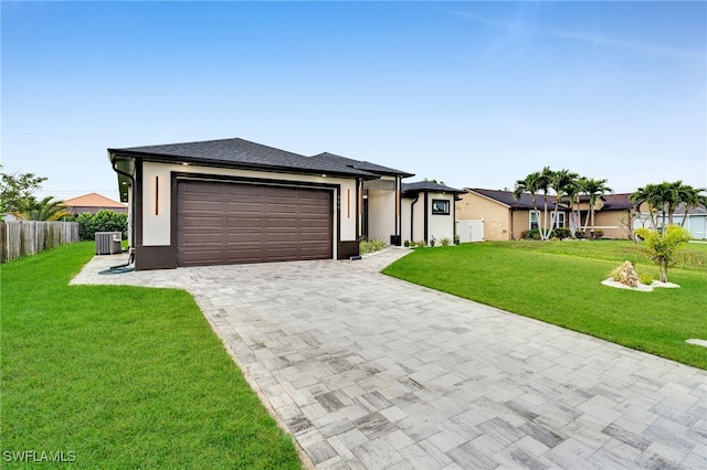 view of front of house featuring stucco siding, decorative driveway, a front yard, an attached garage, and central AC unit