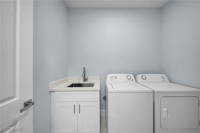 laundry area featuring cabinet space, separate washer and dryer, and a sink