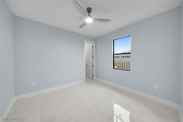 spare room with a ceiling fan and baseboards