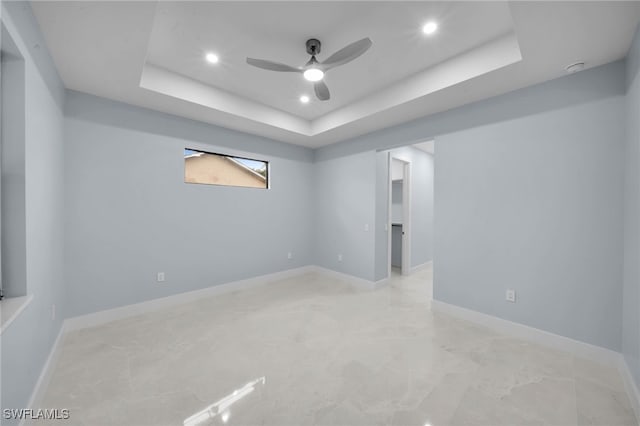 unfurnished room featuring a raised ceiling, recessed lighting, baseboards, and ceiling fan