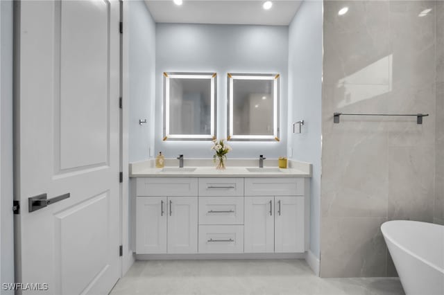 bathroom with double vanity, a soaking tub, recessed lighting, and a sink