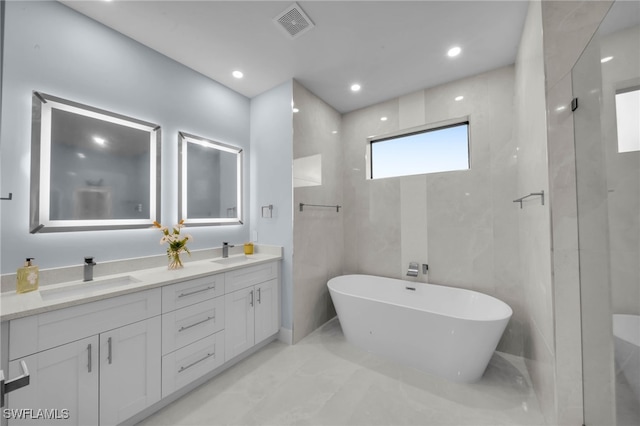 full bathroom with a freestanding bath, double vanity, visible vents, and a sink