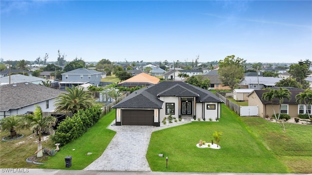 view of front facade with a front lawn, fence, a residential view, decorative driveway, and a garage