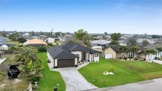 view of front of home featuring decorative driveway, a residential view, a front lawn, and an attached garage